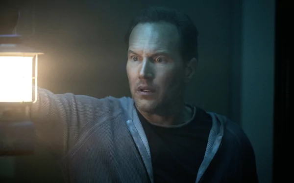 Man holding lantern with intense expression in a suspenseful scene from Insidious: The Red Door, available as HD desktop wallpaper and background.