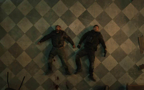Overhead view of two male characters lying on a checkered floor in a scene from Extraction 2, featuring a high-definition desktop wallpaper aesthetic.