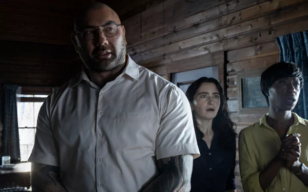 HD wallpaper featuring a scene from Knock at the Cabin with three tense characters indoors, expressing concern and anticipation.