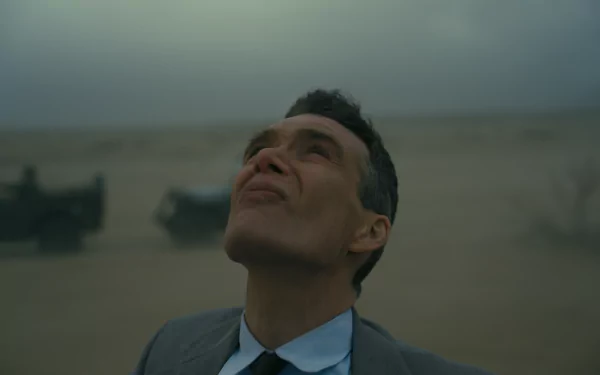 HD desktop wallpaper featuring a thoughtful man in a suit looking skyward with a desolate landscape in the background, reminiscent of Oppenheimer, evoking a contemplative mood.
