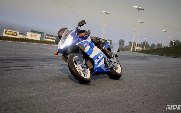 HD desktop wallpaper from the video game Ride 5 featuring a dynamic shot of a blue and white sports motorcycle on a racetrack.