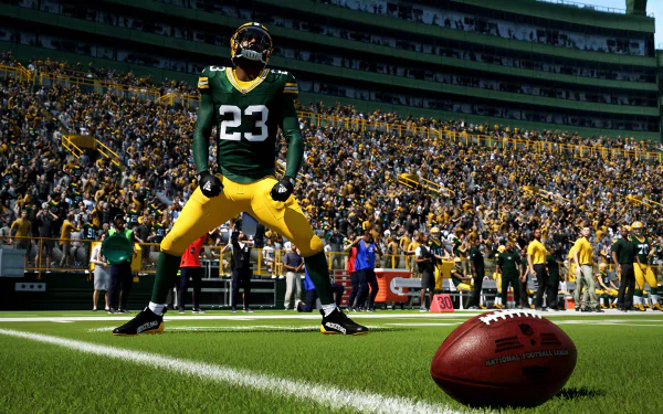 HD desktop wallpaper from Madden NFL 24 featuring a player in green and yellow uniform standing on the field, with a football in the foreground and a packed stadium in the background.