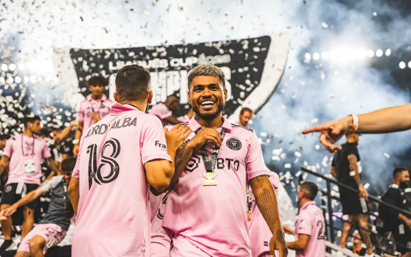 HD desktop wallpaper of Jordi Alba celebrating with an Inter Miami CF teammate, surrounded by confetti and fans cheering in the background.