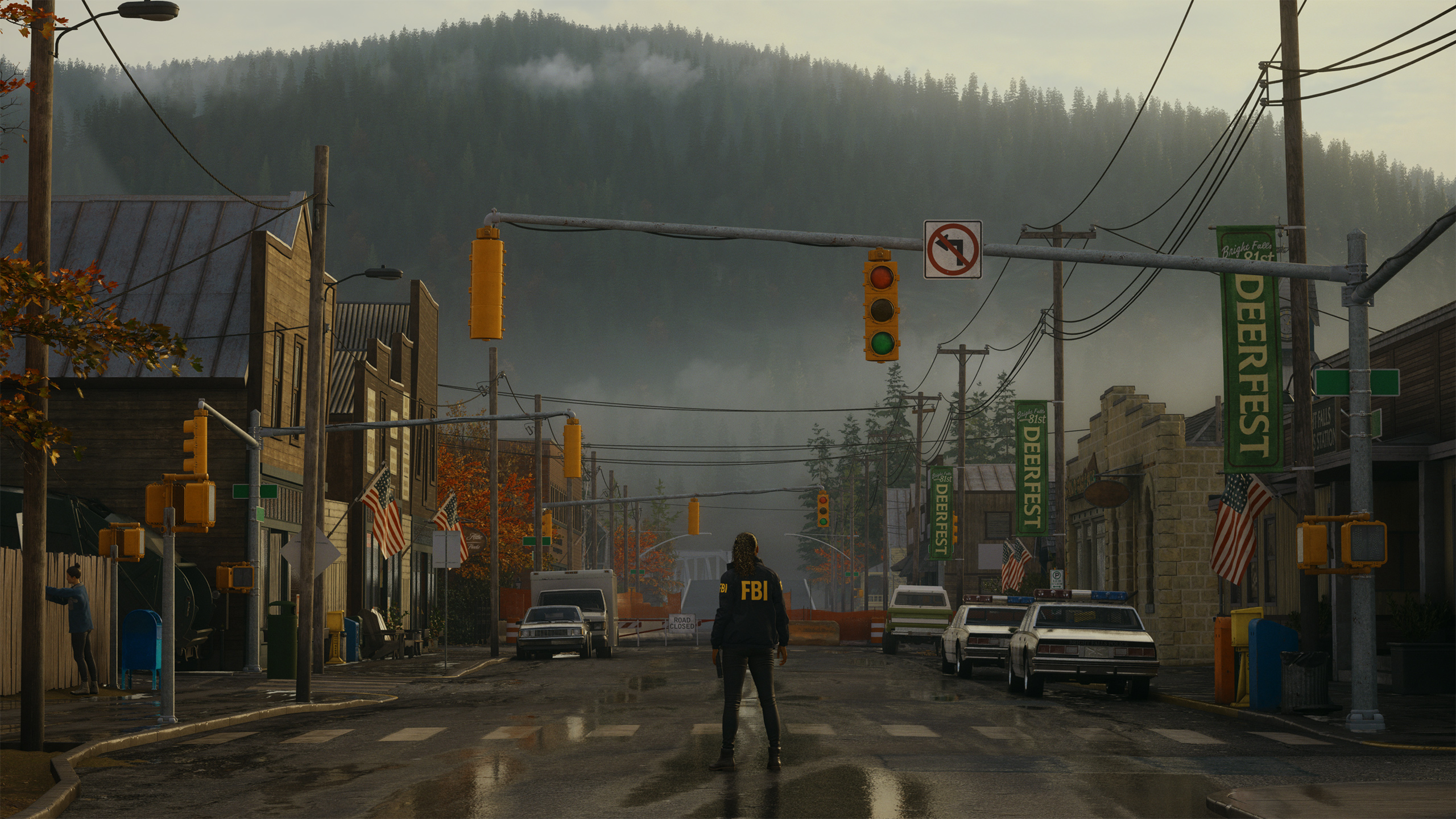 HD desktop wallpaper featuring Alan Wake 2 with a mysterious figure standing in the center of a foggy, small-town street, surrounded by forested hills in the background, setting a suspenseful scene.
