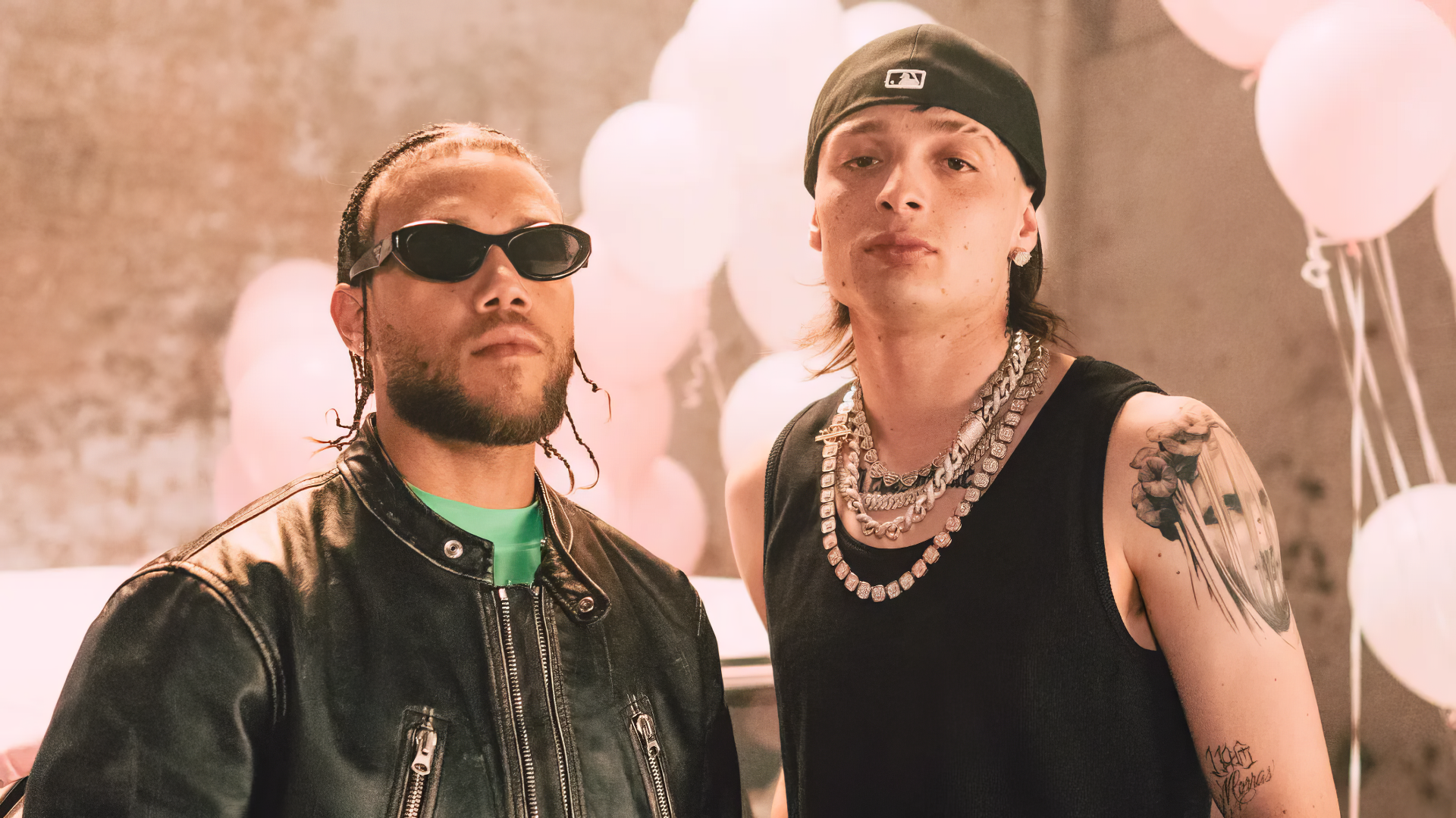 HD desktop wallpaper featuring music artist Peso Pluma, with two men in stylish outfits standing in front of a backdrop with balloons.