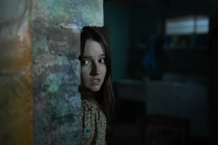 HD desktop wallpaper of Kaitlyn Dever in No One Will Save You looking anxiously around a corner.
