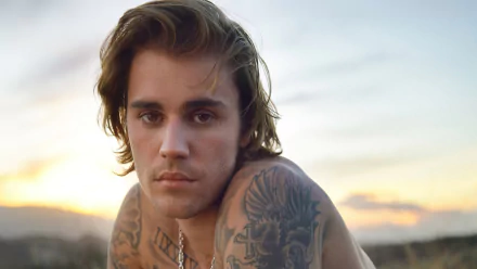 HD desktop wallpaper featuring a portrait of a popular male singer with tattoos against a sunset background.