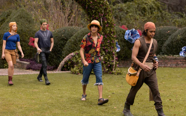 A vibrant scene from the live-action TV show One Piece, featuring four characters walking through a lush garden setting, showcasing their adventurous spirit and colorful costumes.