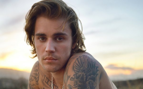 HD desktop wallpaper featuring a portrait of a popular male singer with tattoos against a sunset background.