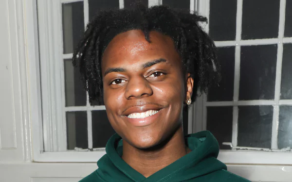 HD desktop wallpaper featuring a smiling individual with black dreadlocks wearing a green hoodie, tagged as IShowSpeed, against a window backdrop.