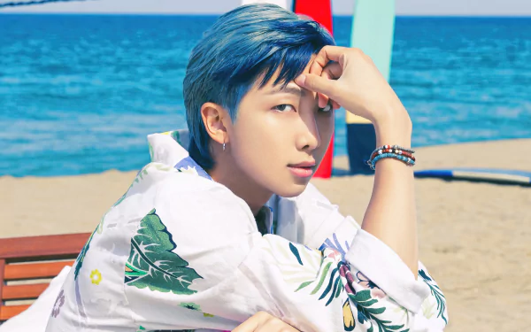 Kim Nam-joon of BTS sitting by the beach, a vibrant HD wallpaper for desktops.
