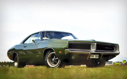 HD desktop wallpaper featuring a classic green Dodge Charger RT parked on grass under a clear sky, showcasing the vehicle's iconic muscle car design.