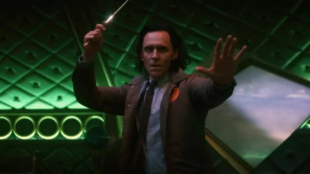 Tom Hiddleston as Loki, raising a hand and wielding a glowing object, set against a striking green backdrop in a scene from the TV show Loki. High-definition wallpaper.
