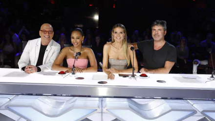 Judges panel from America's Got Talent TV show smiling at their desk for an HD desktop wallpaper background.