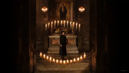 HD wallpaper of a dark, atmospheric scene from 'The First Omen' movie, featuring a mysterious figure standing in a candlelit room with ornate decorations.