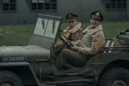 HD wallpaper featuring two characters from the TV show 'Masters of the Air' sitting in a vintage military jeep against a backdrop of wartime structures.