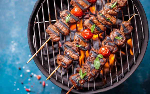 Grilled skewers with marinated meat and cherry tomatoes sizzle over a charcoal BBQ, set against a vibrant blue background, creating a mouthwatering HD wallpaper.