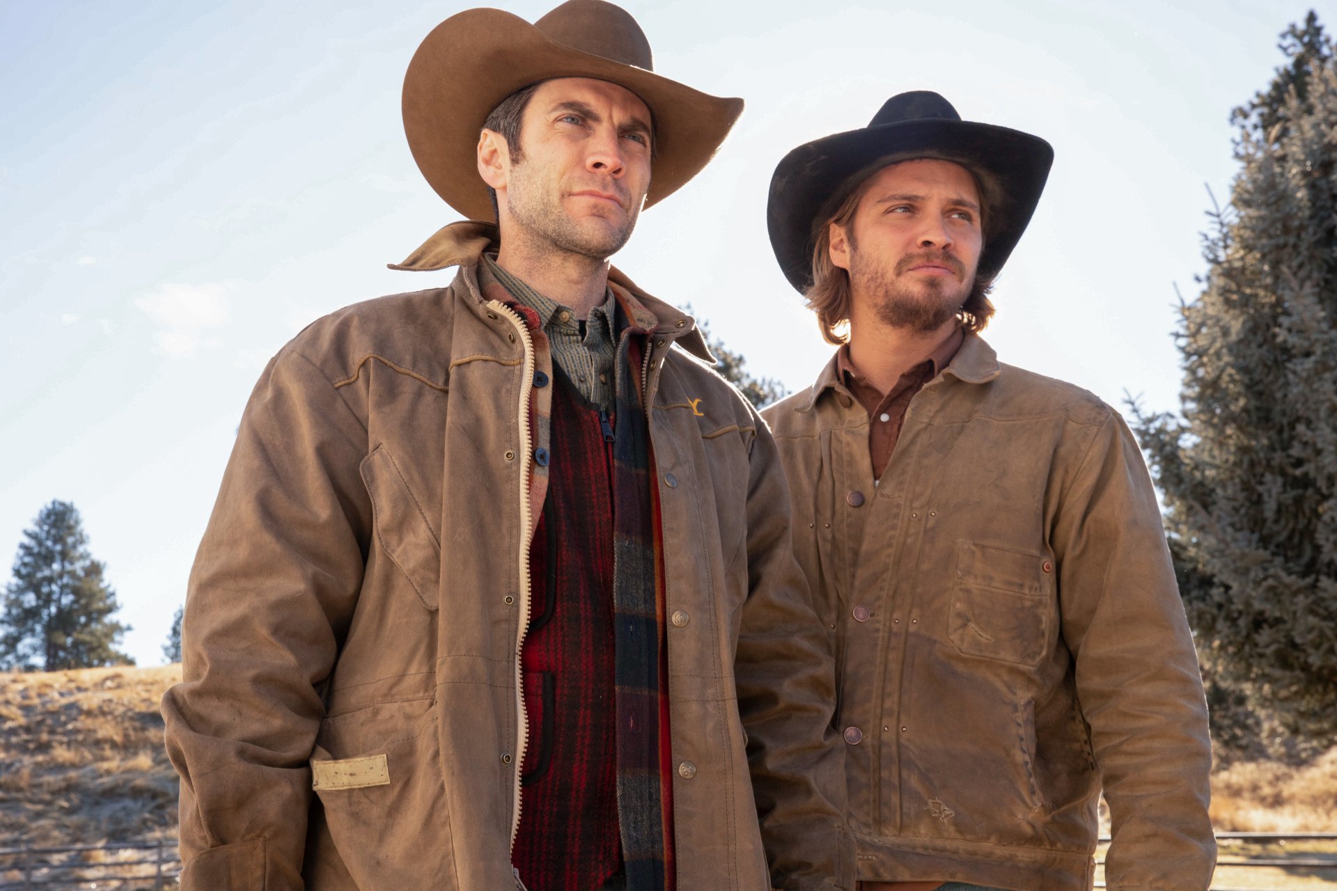 HD desktop wallpaper featuring two characters from the TV show Yellowstone, standing in a rural outdoor setting with cowboy hats and rugged attire.