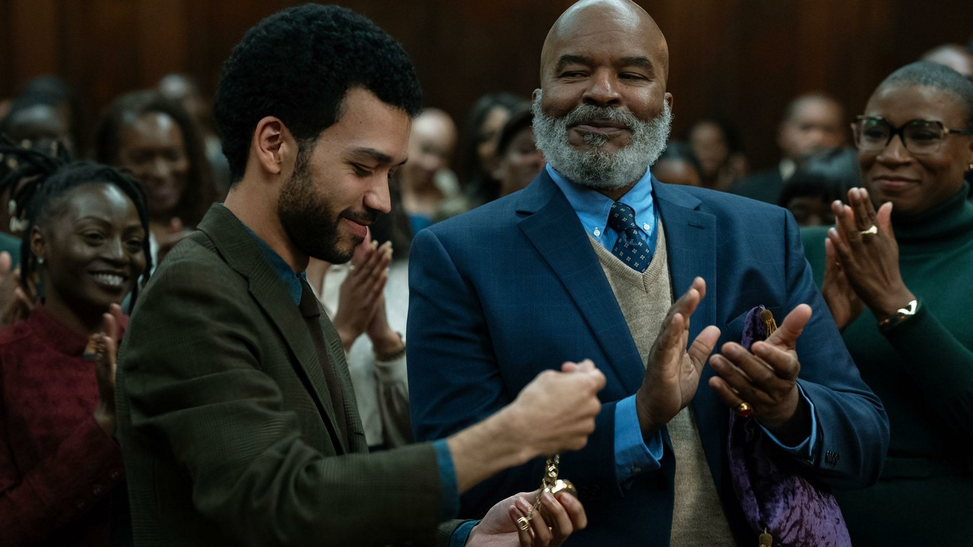 HD wallpaper featuring a scene from the TV show The American Society of Magical Negroes with two male actors engaging in applause in a courtroom setting, evoking a sense of accomplishment and unity among the audience.