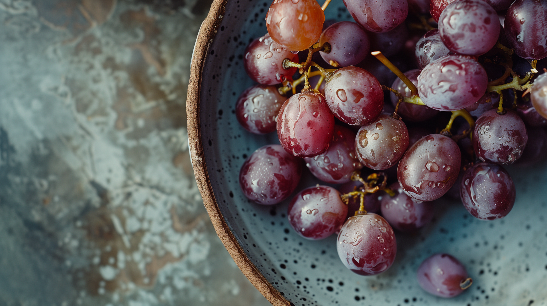 A close-up of glistening grapes in a rustic bowl, set against a textured background, creating a vibrant and refreshing HD desktop wallpaper.