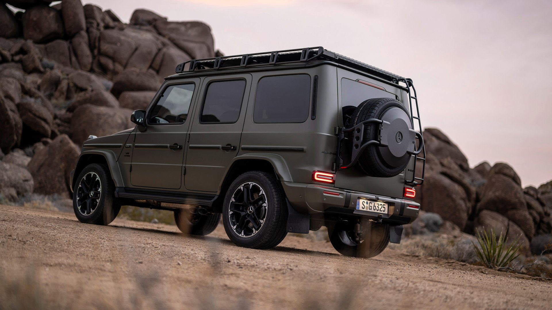 A sleek Mercedes-AMG G63 in a striking matte green finish parked on a rugged terrain, showcasing its powerful design and adventurous spirit against a natural backdrop.