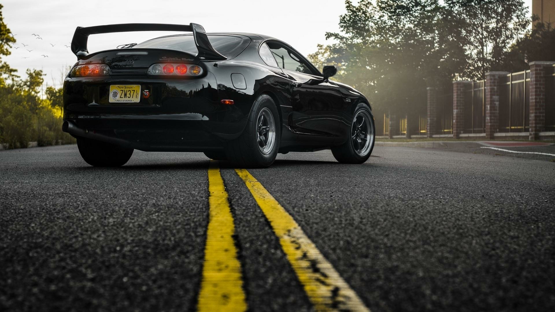HD wallpaper of a black Toyota Supra parked on a road with a yellow dividing line, suitable as a desktop background.