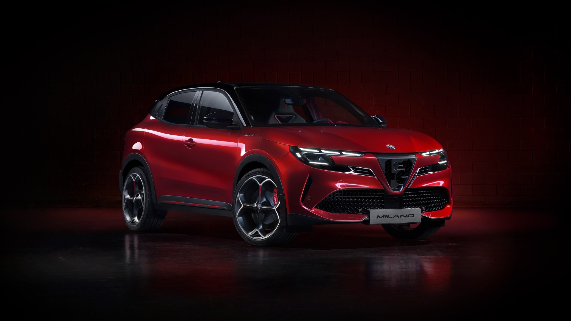 A red Alfa Romeo Milano Veloce on a dark background, showcased as an HD desktop wallpaper.