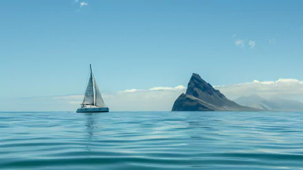 HD wallpaper featuring a catamaran sailing the ocean near an island with a prominent peak under a clear blue sky.