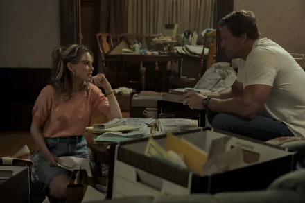 HD wallpaper featuring a scene from the movie Ordinary Angels with two characters engaged in a conversation amidst a cluttered room filled with papers and boxes.