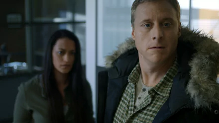 HD wallpaper featuring a scene from the TV show Resident Alien with a man in a coat in the foreground and a woman in the background.