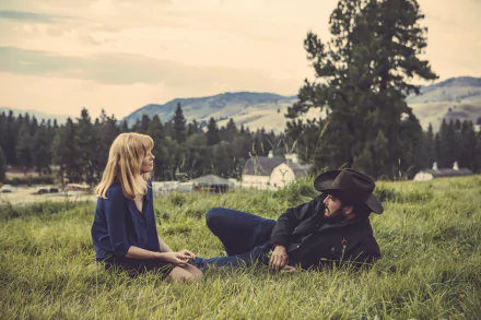 HD wallpaper featuring two characters from the TV show Yellowstone, conversing in a grassy field with a rustic backdrop.