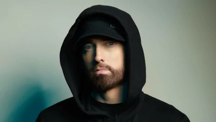 HD desktop wallpaper of a rapper in a black hoodie with an intense gaze, embodying a striking music-themed background.