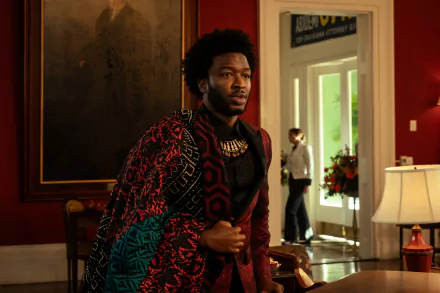 Actor portraying a character in the TV show Parish (2024) wearing a bold patterned jacket, poised in a richly decorated room, suitable as an HD desktop wallpaper and background.