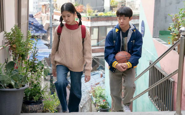 HD wallpaper from the movie Past Lives featuring two characters walking down outdoor stairs in a residential area.