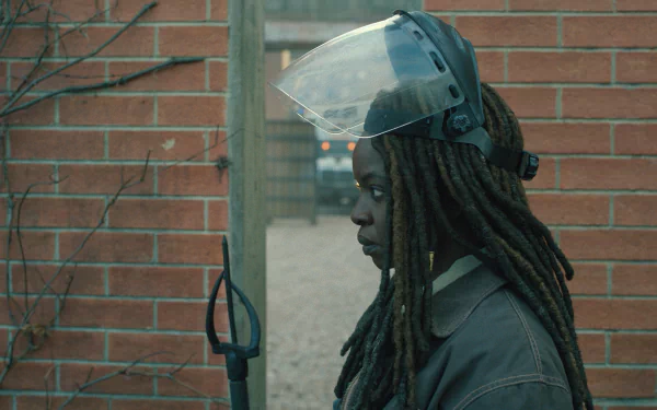HD desktop wallpaper featuring a side profile of a character from the TV show The Walking Dead: The Ones Who Live, equipped with a protective headgear, set against a brick wall backdrop.