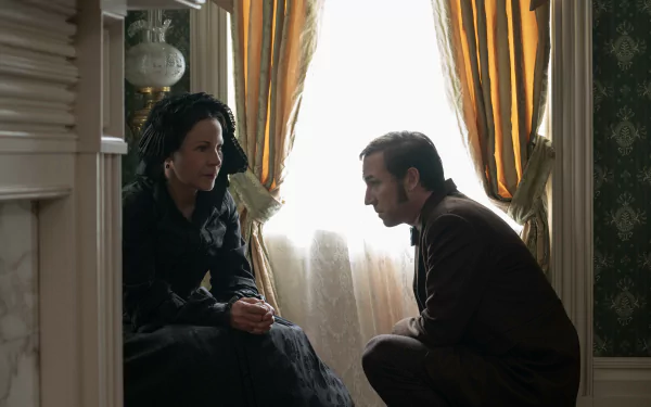 A tense moment between two characters in the TV show *Manhunt (2024)*, featuring a dimly lit room with elegant decor and soft sunlight filtering through the curtains.