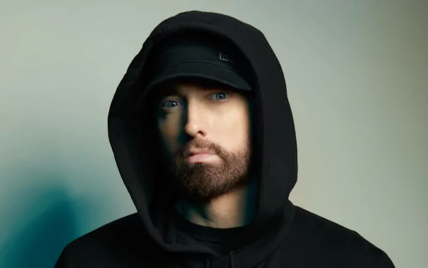 HD desktop wallpaper of a rapper in a black hoodie with an intense gaze, embodying a striking music-themed background.