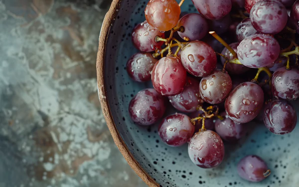 A close-up of glistening grapes in a rustic bowl, set against a textured background, creating a vibrant and refreshing HD desktop wallpaper.