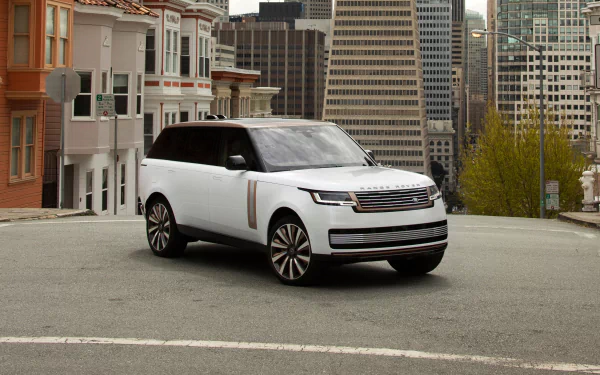 HD wallpaper featuring a white Range Rover P530 LWB parked on a city street, showcasing its sleek design against a backdrop of tall buildings.