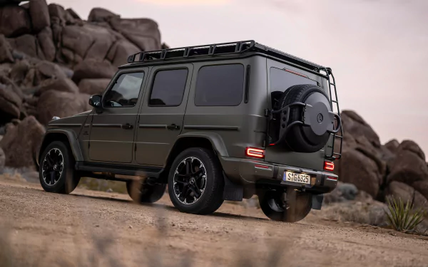 A sleek Mercedes-AMG G63 in a striking matte green finish parked on a rugged terrain, showcasing its powerful design and adventurous spirit against a natural backdrop.