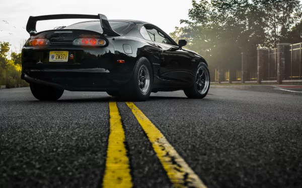 HD wallpaper of a black Toyota Supra parked on a road with a yellow dividing line, suitable as a desktop background.