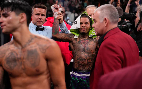 HD desktop wallpaper featuring a boxing scene with a victorious boxer wearing a hooded robe, surrounded by officials and another boxer in the foreground.