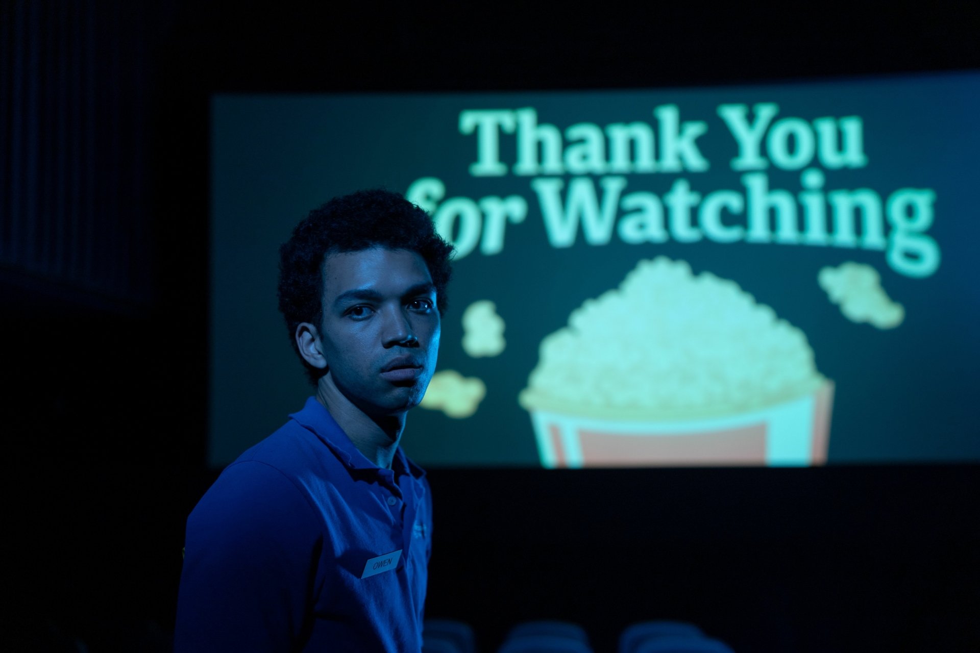 HD desktop wallpaper from I Saw the TV Glow featuring Justice Smith in a cinema with a Thank You for Watching screen in the background.