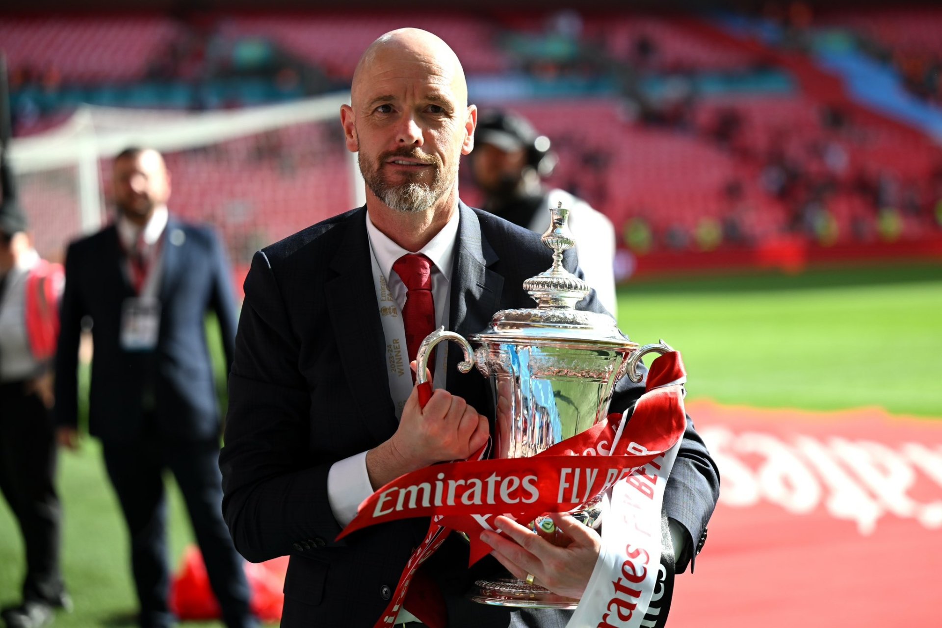 A man holding a trophy in a soccer stadium, tagged with Sports, soccer, Manchester United F.C. This HD desktop wallpaper and background captures a moment of victory.