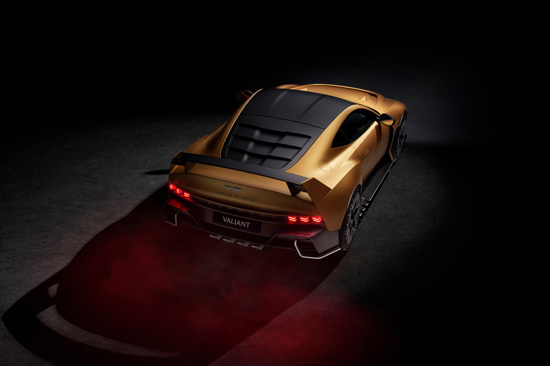 HD desktop wallpaper featuring the sleek and powerful Aston Martin Valiant, captured from a rear angle, showcasing its dynamic design and illuminated taillights against a dark background.