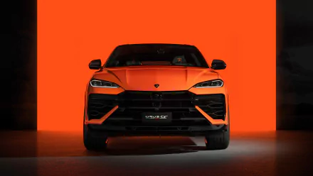 HD desktop wallpaper of a Lamborghini Urus displayed against an orange background, showcasing the front view of the sleek, orange sports car.
