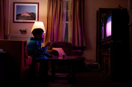 HD wallpaper from the movie I Saw the TV Glow, featuring a person watching television in a dimly lit room with ambient lighting.