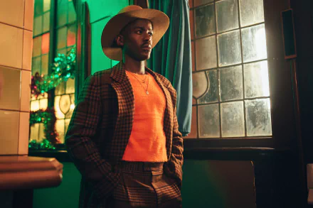 HD desktop wallpaper featuring Ncuti Gatwa from the 2023 TV show Doctor Who, styled in a plaid suit and hat, standing by a window.