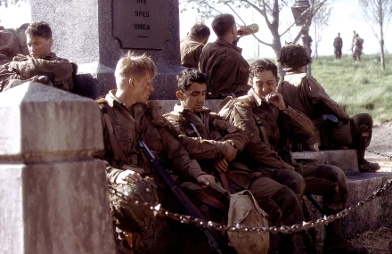 HD wallpaper featuring soldiers from the TV show Band of Brothers resting near a monument, capturing a moment of camaraderie and respite.