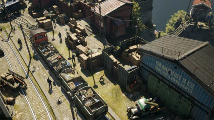 HD desktop wallpaper and background of Eriksholm: The Stolen Dream video game, showcasing a train yard with industrial buildings, tracks, and numerous characters and crates scattered around.

